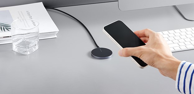 Une main déconnectant un chargeur MagSafe pour iPhone de son téléphone.