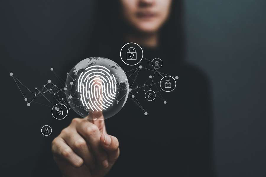 Une personne touche une interface holographique représentant une empreinte numérique et un globe terrestre entouré d'icônes de sécurité.